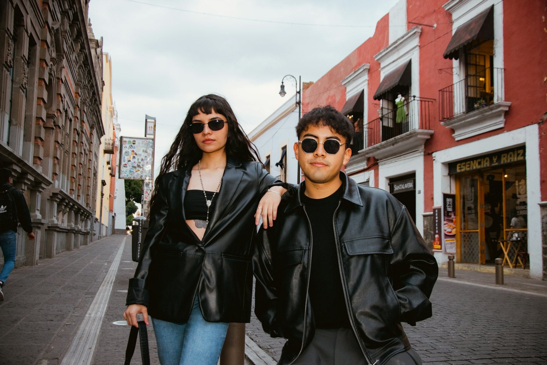 Two people in black leather jackets on a colourful city street