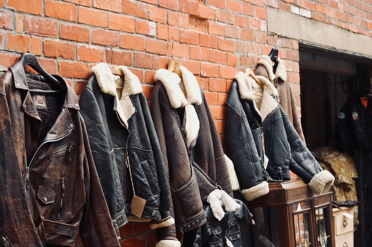 Shearling-collar leather jackets hanging on a brick wall