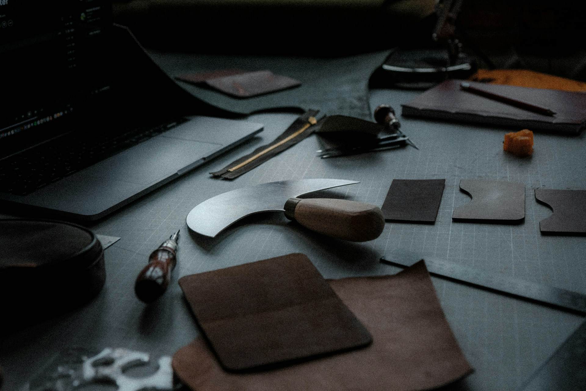 Leatherworking tools and hand-cut leather pieces on a workbench